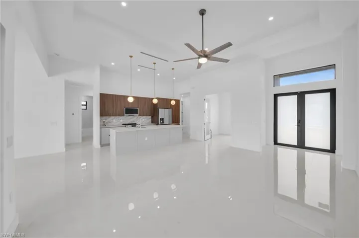 Unfurnished living room with a high ceiling, a ceiling fan, french doors, and recessed lighting