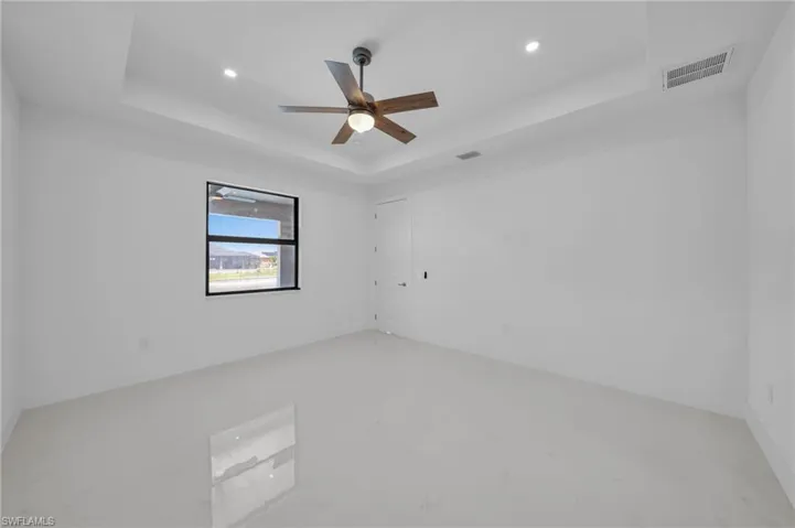 Empty room featuring recessed lighting, a ceiling fan, visible vents, and a raised ceiling
