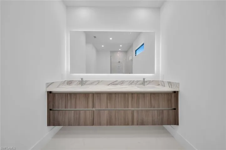 Full bathroom with double vanity, baseboards, recessed lighting, marble finish floor, and a shower