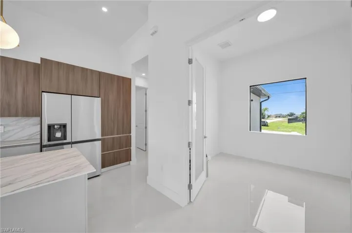 Kitchen featuring recessed lighting, modern cabinets, brown cabinetry, stainless steel refrigerator with ice dispenser, and light countertops