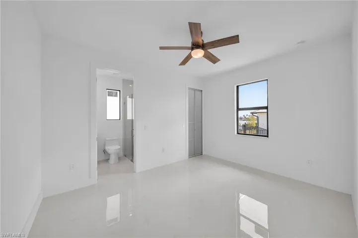 Unfurnished bedroom with a ceiling fan and ensuite bathroom
