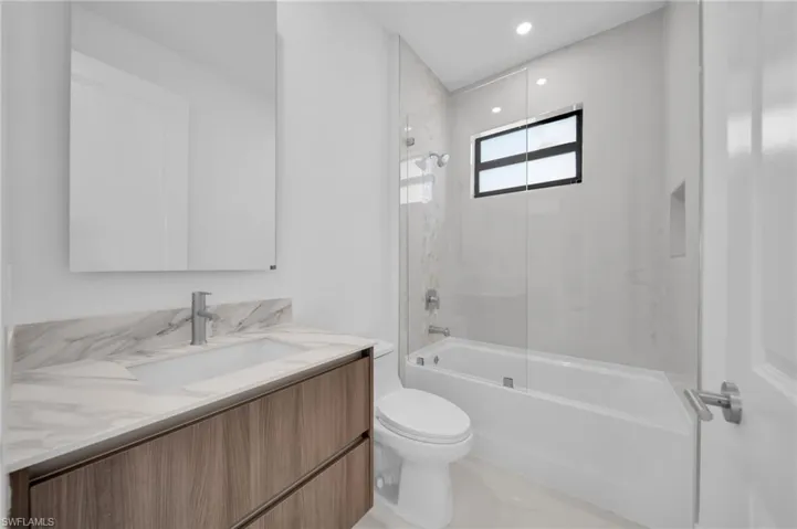 Full bath with toilet, vanity,  shower combination, and recessed lighting