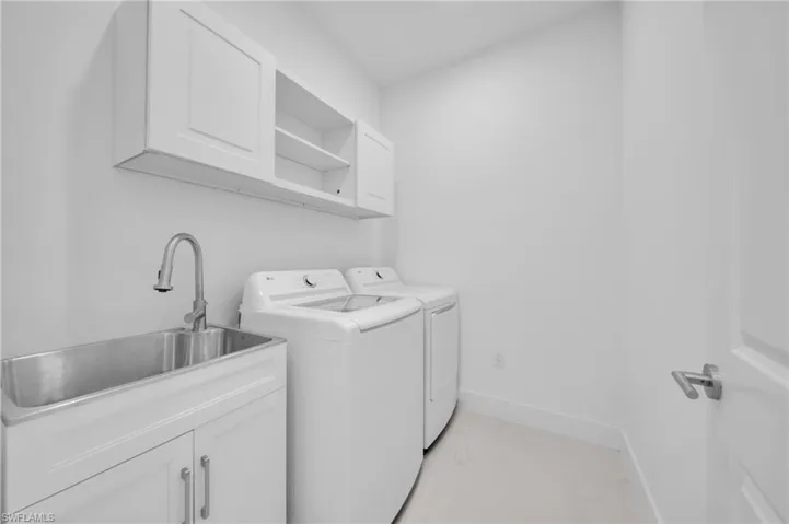 Laundry area with washing machine and clothes dryer, a sink, marble finish floor, cabinet space, and baseboards