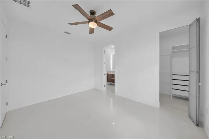 Unfurnished bedroom with a closet, a spacious closet, concrete flooring, baseboards, and visible vents