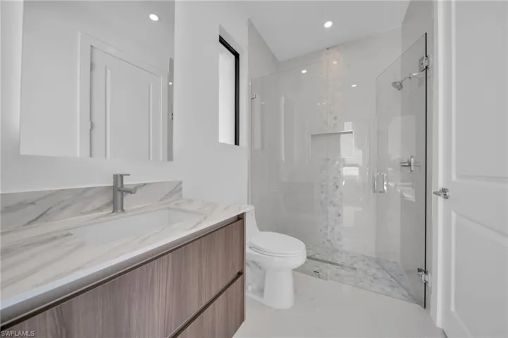 Bathroom featuring a stall shower, vanity, recessed lighting, and toilet