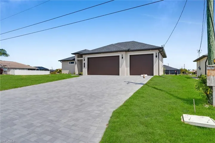 Prairie-style house featuring stucco siding, an attached garage, a front yard, and decorative driveway