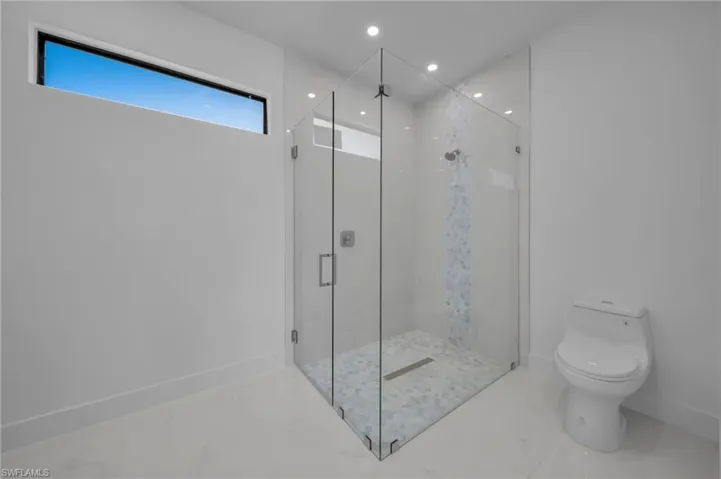 Full bath featuring recessed lighting, marble finish floor, toilet, a marble finish shower, and baseboards
