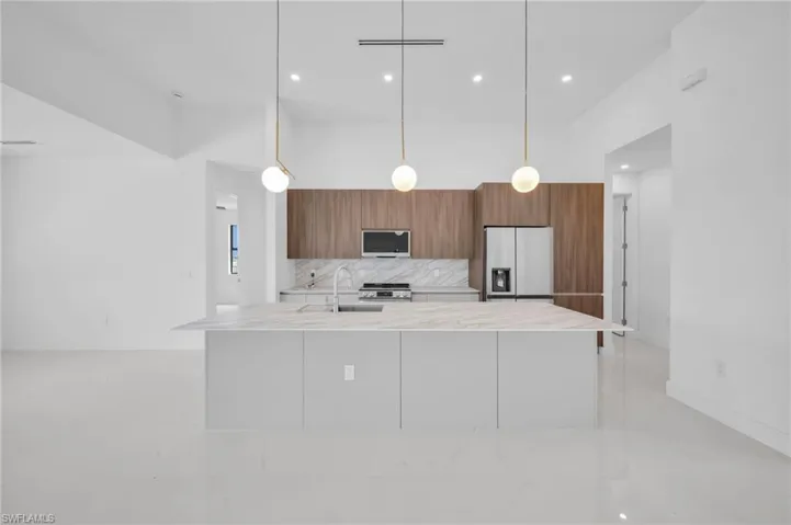 Kitchen with stainless steel appliances, light countertops, backsplash, modern cabinets, and brown cabinetry