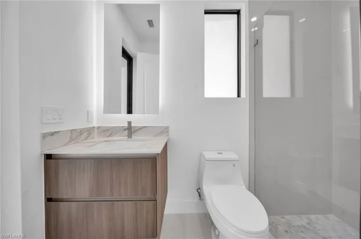 Full bathroom featuring visible vents, toilet, vanity, and a walk in shower