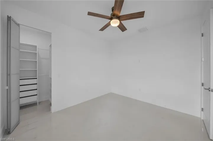 Unfurnished bedroom with visible vents, a spacious closet, marble finish floor, a closet, and ceiling fan