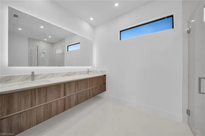 Full bath featuring a sink, a marble finish shower, double vanity, visible vents, and recessed lighting