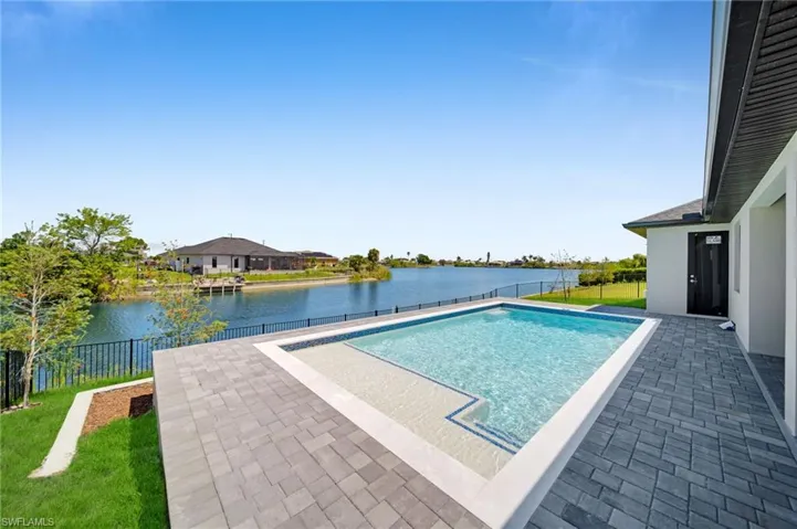 View of swimming pool with a patio, a fenced backyard, a fenced in pool, and a water view
