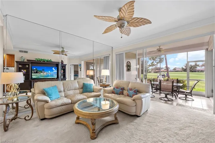 Living room with crown molding, a sunroom, and view of golf course