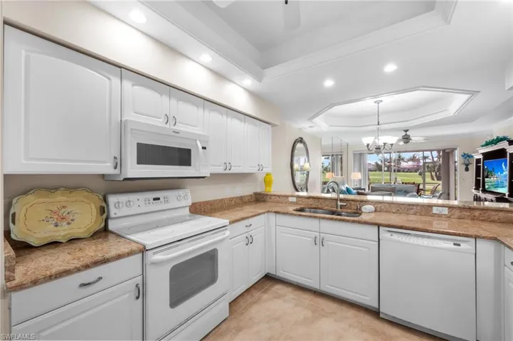 Kitchen featuring a tray ceiling, white appliances, a ceiling fan, white cabinetry, and recessed lighting
