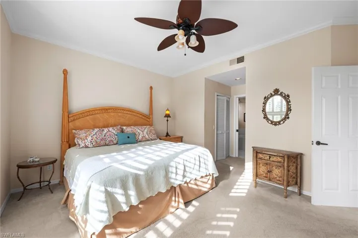 Carpeted bedroom featuring ornamental molding, a closet, and a ceiling fan
