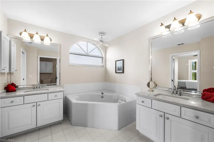 Bathroom featuring two vanities, ceiling fan, a bath, and connected bathroom