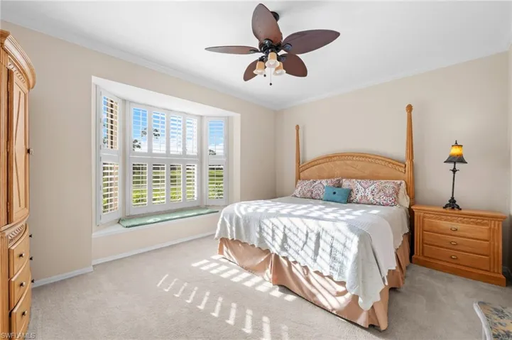 Bedroom with ornamental molding, a ceiling fan, and light colored carpet