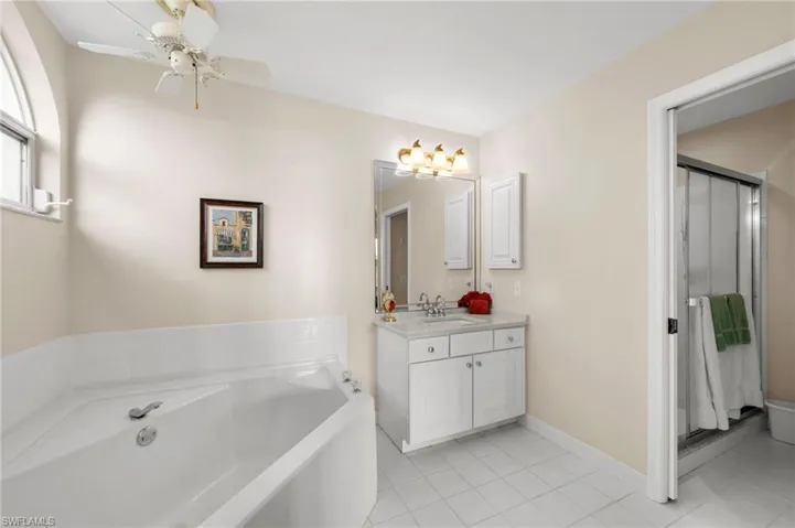 Bathroom with vanity, a garden tub, light tile patterned floors, a shower stall, and ceiling fan