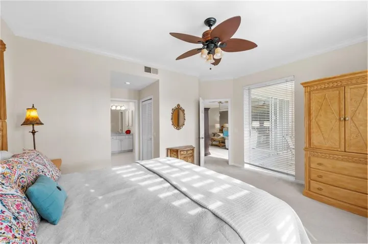 Bedroom featuring ornamental molding, light carpet, a ceiling fan, a closet, and ensuite bathroom