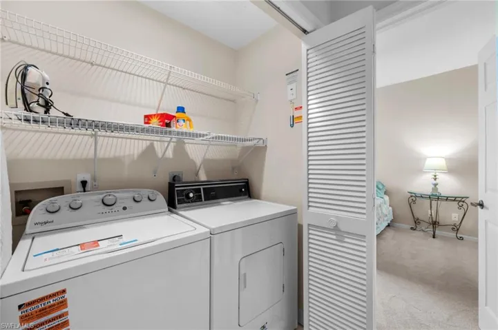 Laundry area featuring light colored carpet and washer and clothes dryer