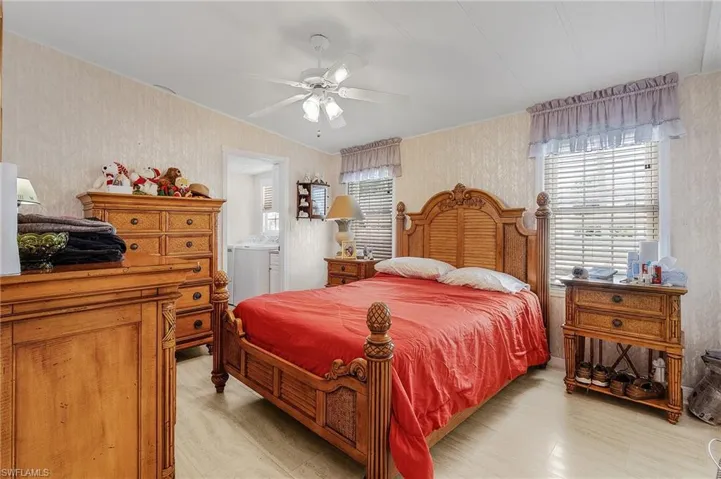 Bedroom with ensuite bathroom, light hardwood / wood-style flooring, multiple windows, and ceiling fan
