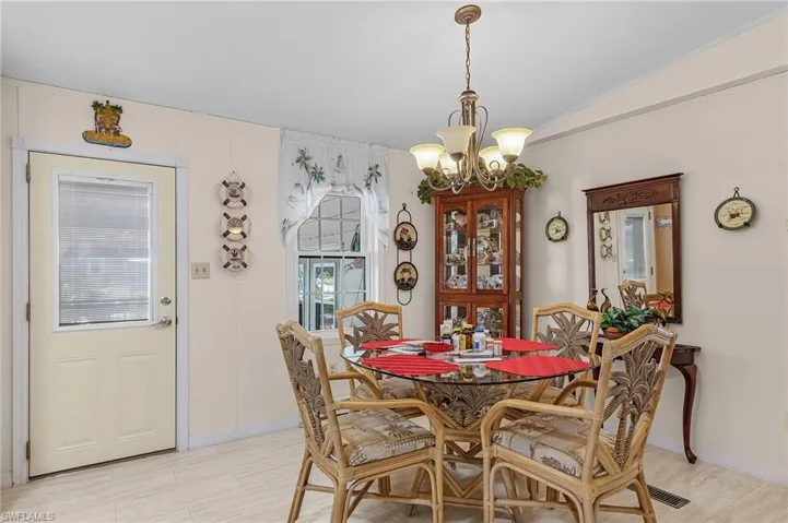 Dining area featuring an inviting chandelier, light tile patterned floors, and vaulted ceiling