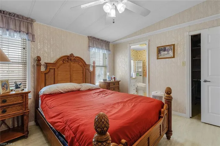 Bedroom with lofted ceiling, light hardwood / wood-style flooring, ensuite bathroom, and ceiling fan