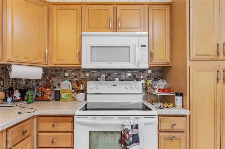 Kitchen featuring tasteful backsplash and white appliances