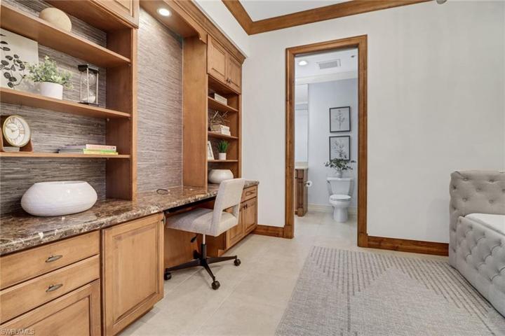 Built in desk with shelving and grasscloth wallpaper accen