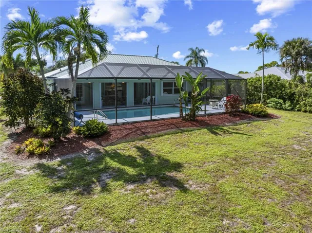 Rear view of property with a patio, an outdoor pool, a sunroom, a lawn, and a lanai