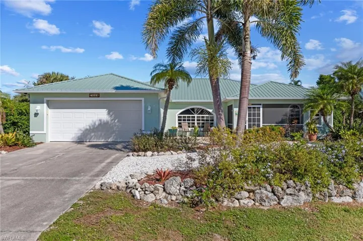Ranch-style home featuring an attached garage, a metal roof, concrete driveway, and stucco siding
