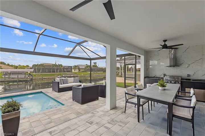 View of patio featuring glass enclosure, a water view, ceiling fan, and an outdoor hangout area