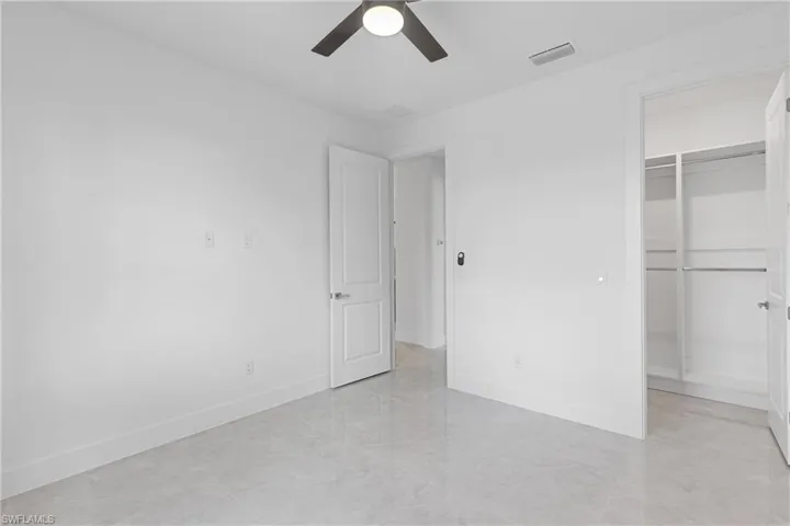 Unfurnished bedroom featuring a spacious closet, ceiling fan, and a closet