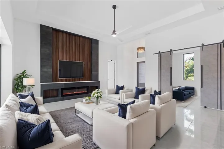 Living room with a barn door, a raised ceiling, a towering ceiling, and a large fireplace