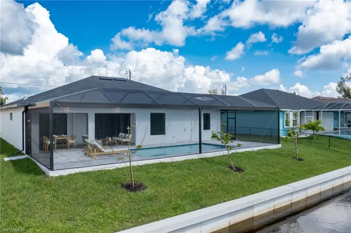 Back of house with glass enclosure, a yard, a patio area, and a pool