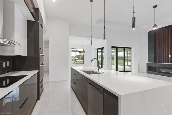 Kitchen featuring ceiling fan, hanging light fixtures, sink, dishwasher, and a spacious island