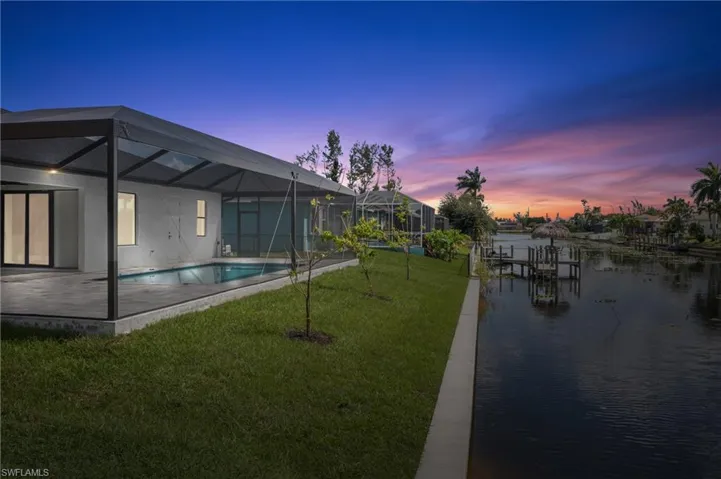 Rear of home featuring sea wall, canal and sunset