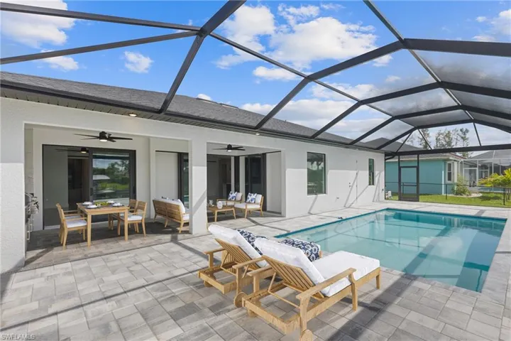 View of swimming pool featuring glass enclosure, an outdoor living space, ceiling fan, and a patio area