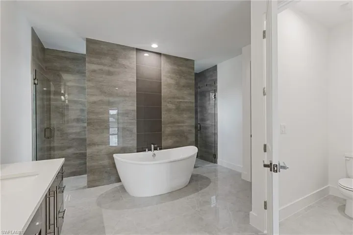 Full bathroom featuring separate shower and tub, vanity, and toilet