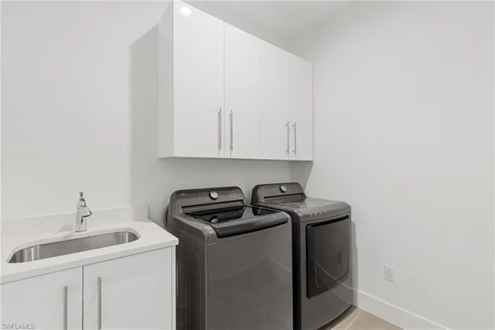 Laundry area featuring washer and clothes dryer, cabinets, and sink