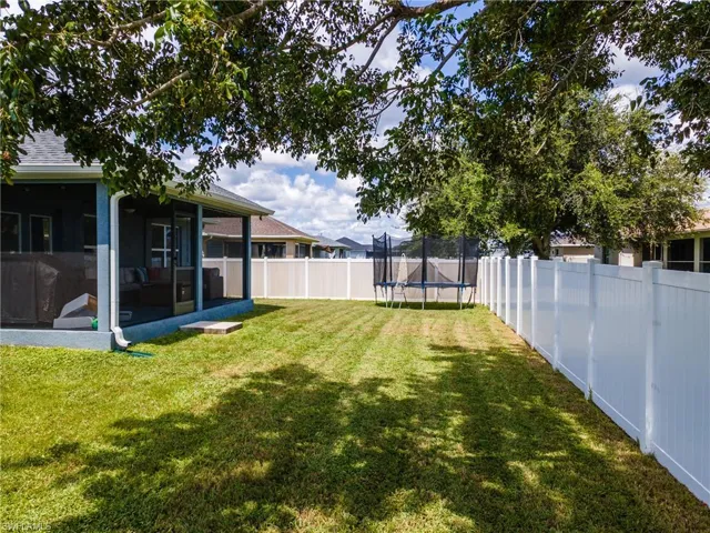 Fenced backyard featuring a sunroom and a trampoline