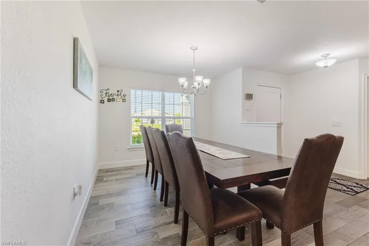 Dining space with light wood-type flooring, a chandelier, and a textured wall
