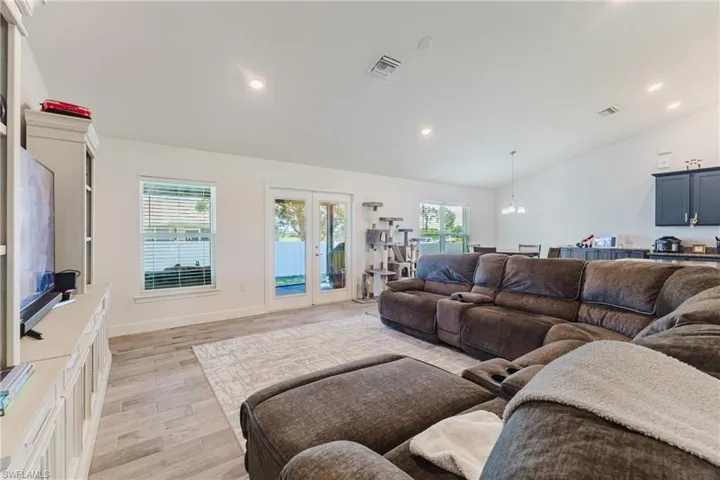 Living room featuring light wood-type flooring, recessed lighting, a chandelier, and high vaulted ceiling