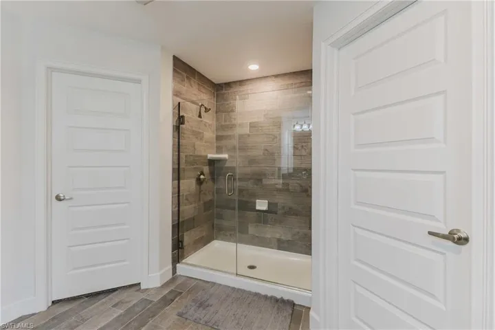 Bathroom with a shower stall, wood finish floors, and recessed lighting
