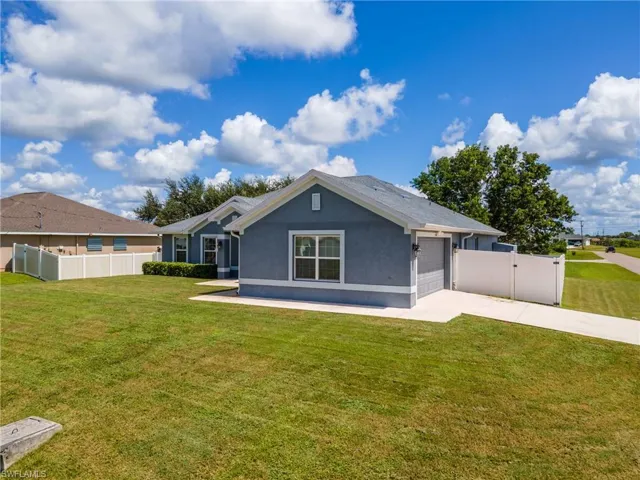 Back of property with stucco siding, a garage, concrete driveway, and a gate