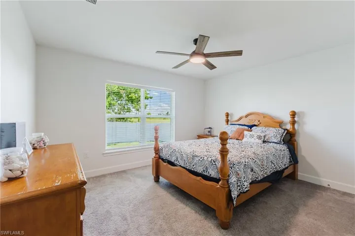 Carpeted bedroom featuring ceiling fan and baseboards