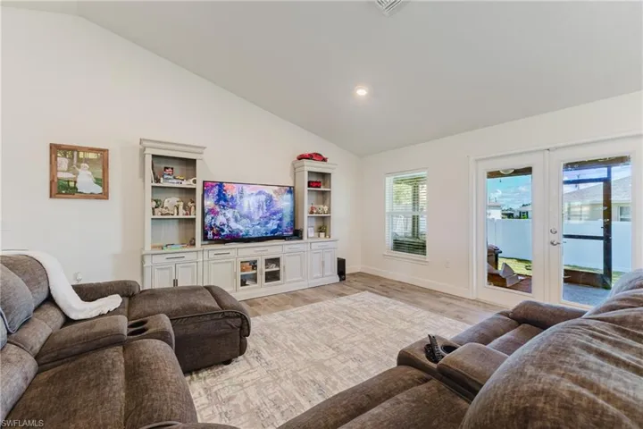 Living room featuring vaulted ceiling, light wood-type flooring, french doors, and recessed lighting
