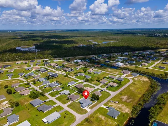 Aerial view of residential area featuring a nearby body of water and a heavily wooded area