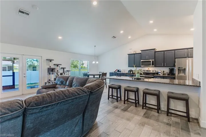 Living area with light wood-style floors, high vaulted ceiling, recessed lighting, french doors, and a chandelier