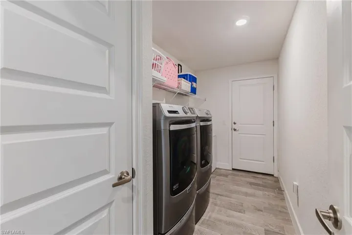 Washroom with light wood-type flooring and washing machine and clothes dryer